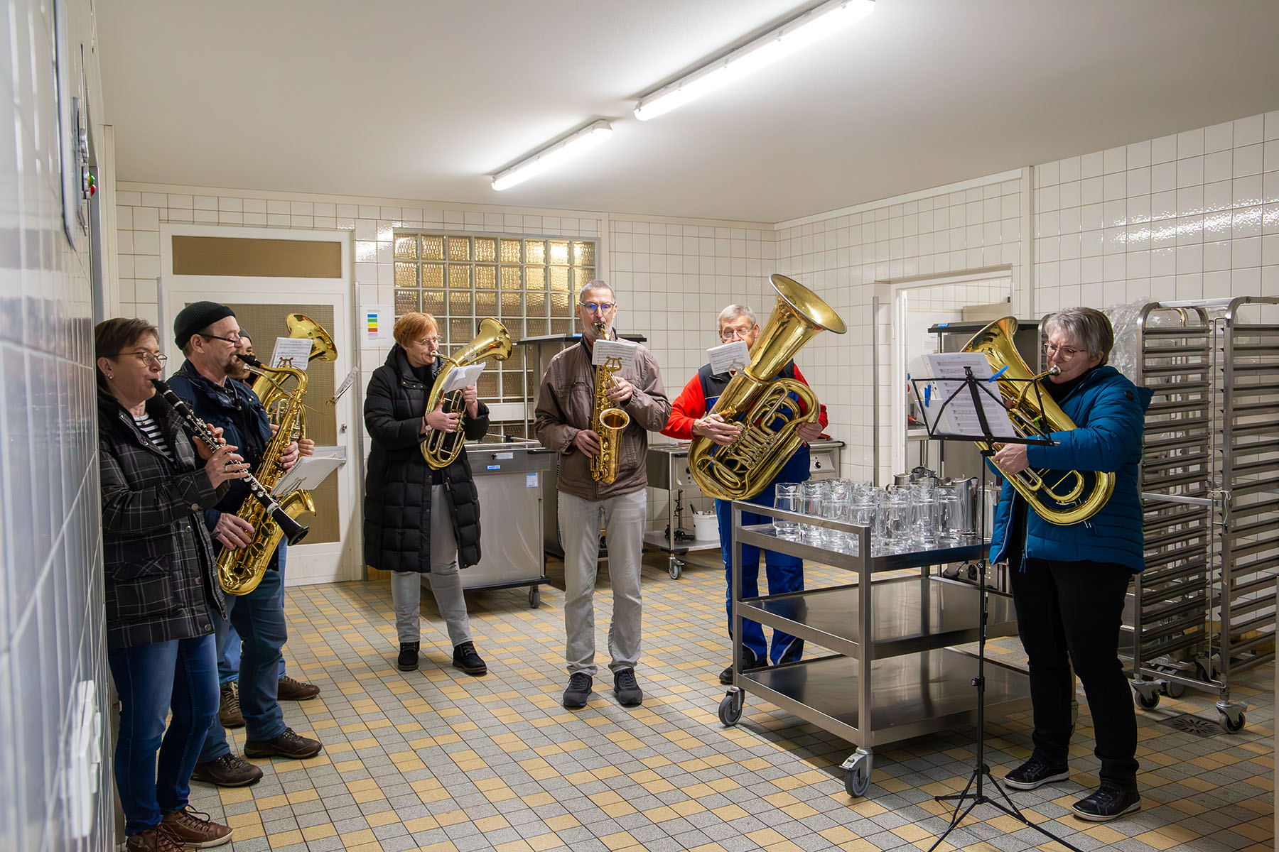 Fünf Musiker mit Blechblasinstrumenten in einer Großküche
