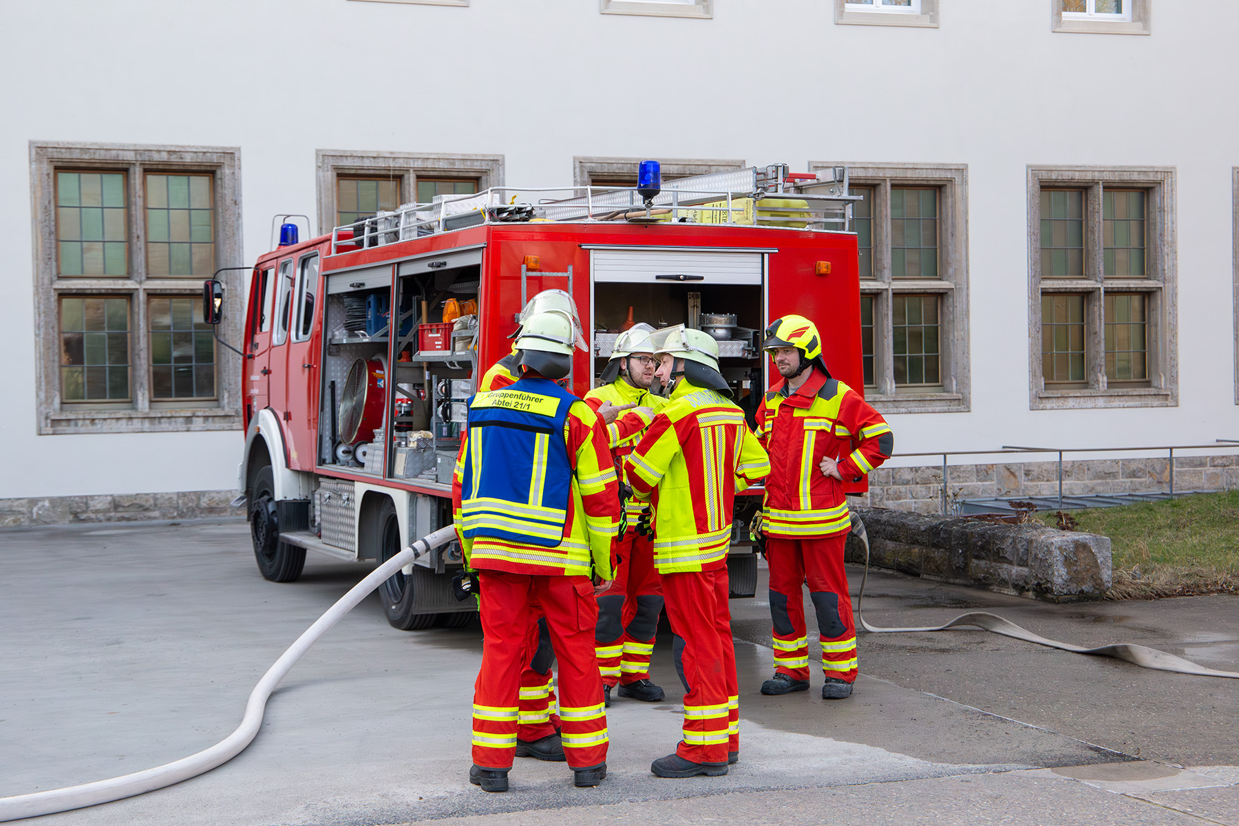 Fünf Männer in Feuerwehruniform vor einem Feuerwehrauto