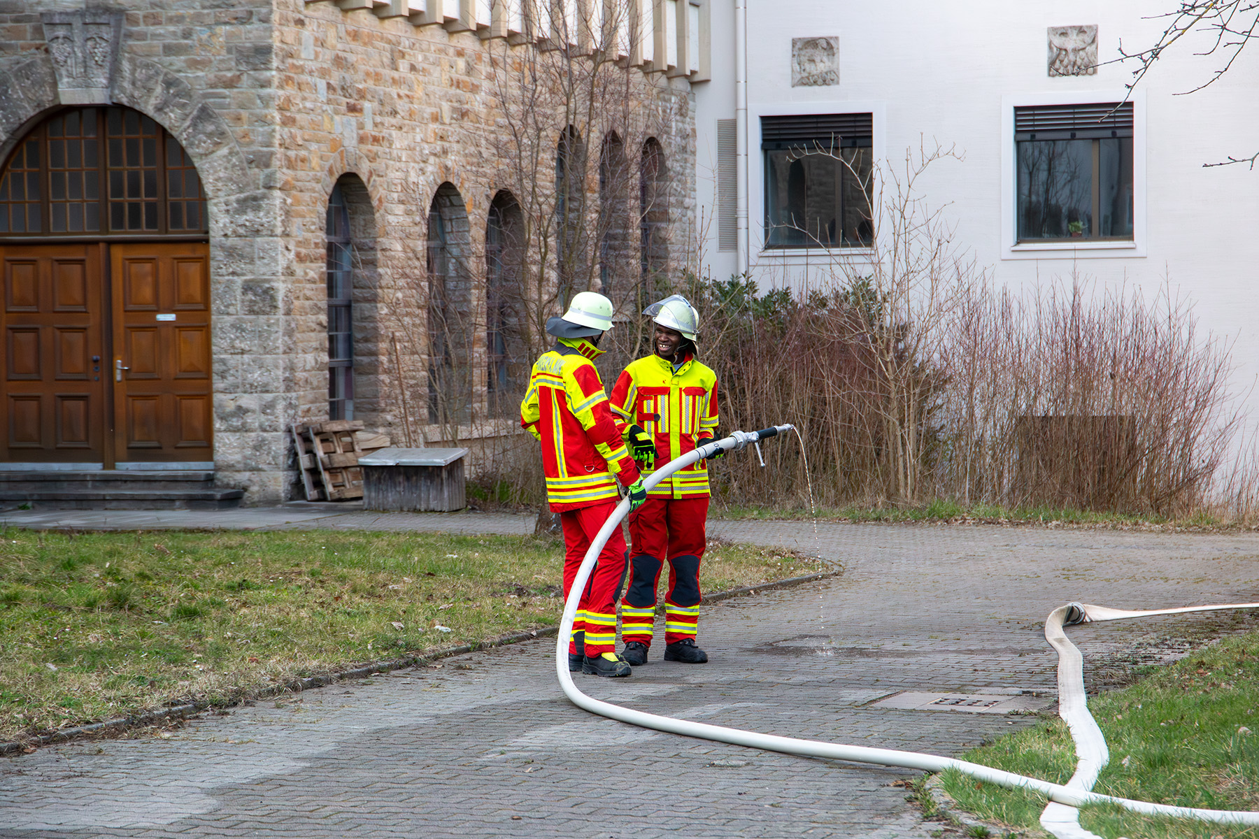 Feuerwehrmann erklärt zweitem Mann den Feuerwehrschlauch