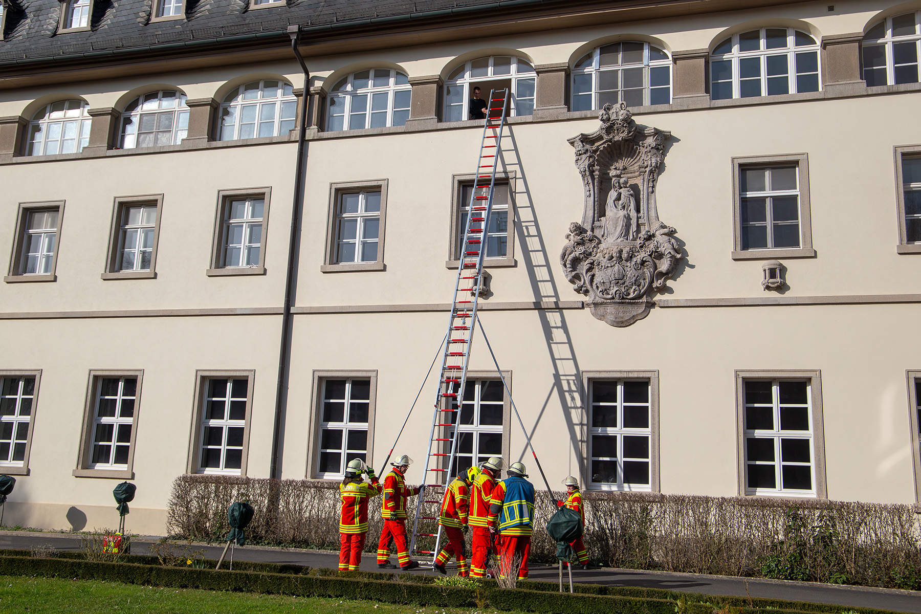 Menschen vor Feuerwehrleiter, die an ein Gebäude lehnt