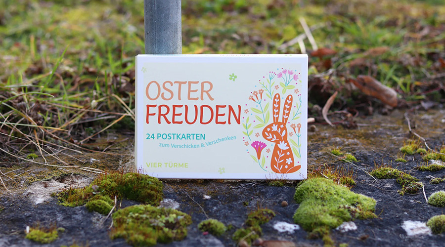 Postkarte mit buntem Hasen auf einer Wiese