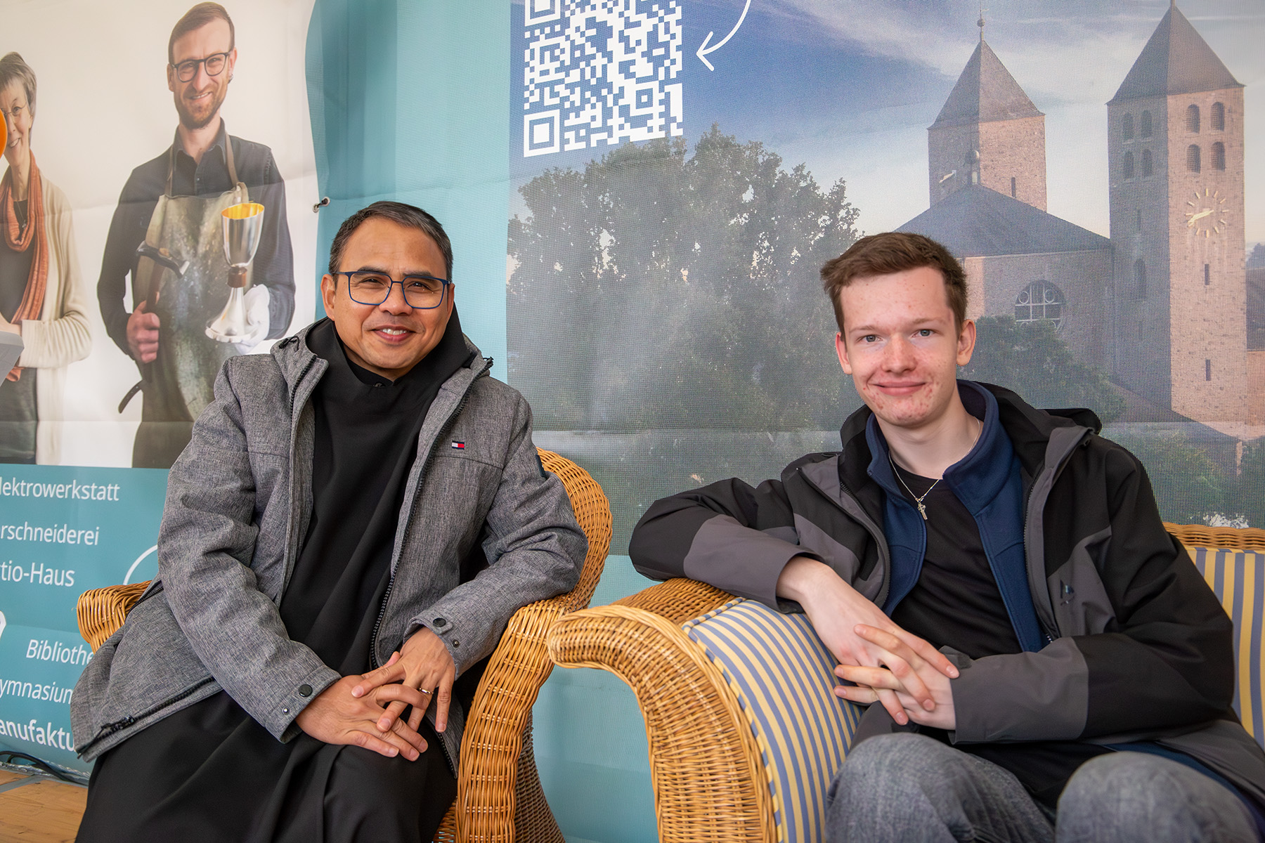 Junger Mönch und junger Mann sitzen am Stand