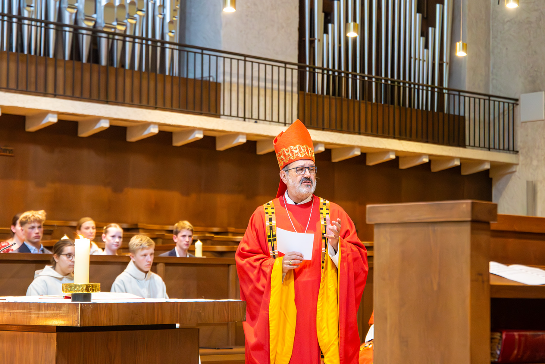 Mann im roten Gewandt und Bischofshut in der Kirche