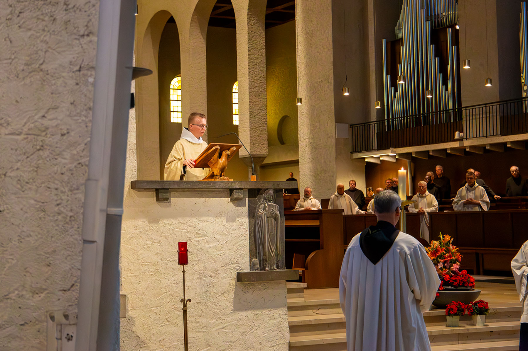 Priester im weißen Gewand mit großem Buch auf der Kanzel
