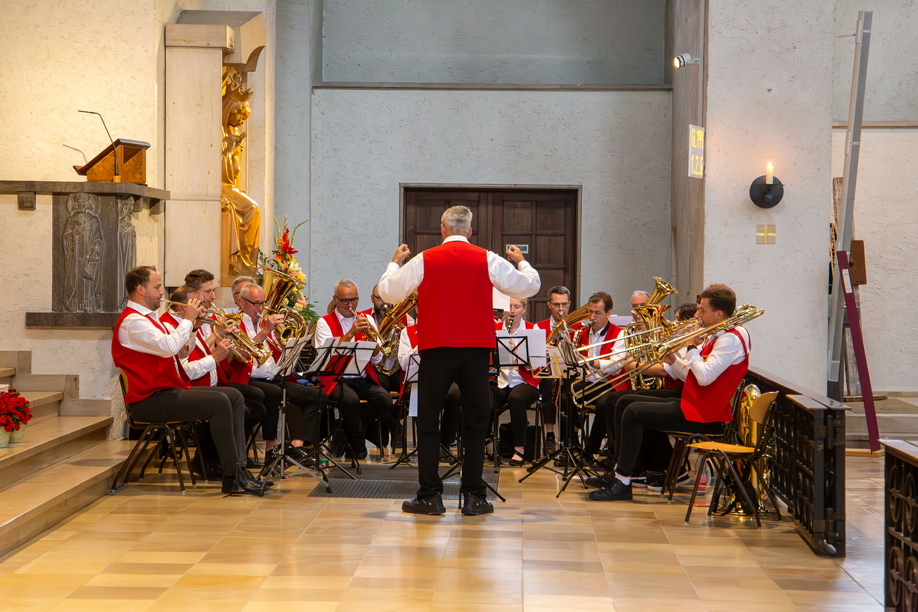 Gruppe von Menschen in rot-weißer Tracht beim Musizieren mit Blasinstrumenten
