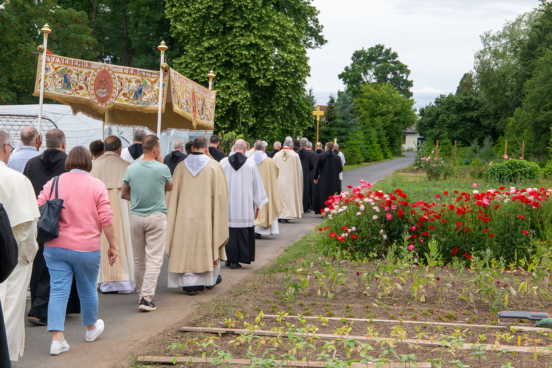 Gruppe von Menschen zieht an einem Blumenbeet vorbei