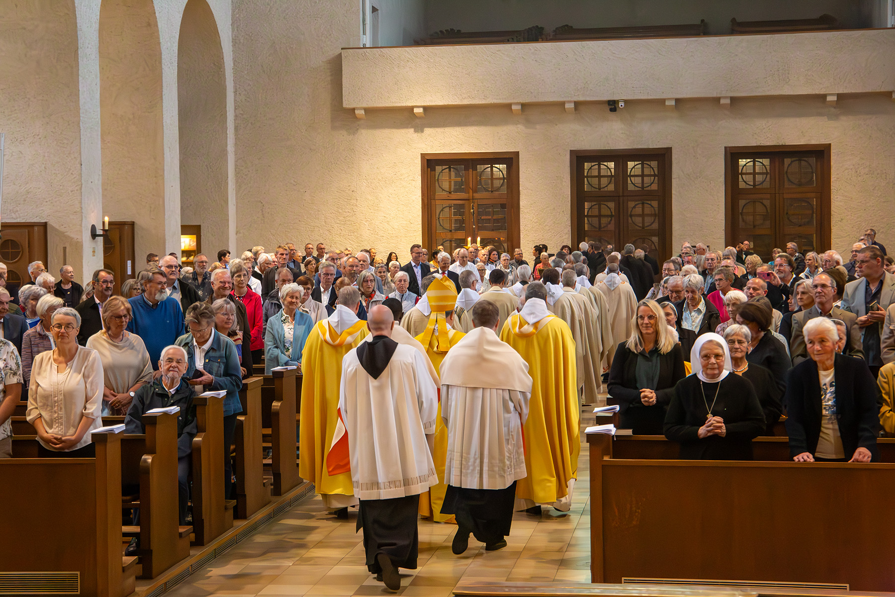 Die Gemeinde steht in den Kirchenbänken während Mönche und Priester ausziehen