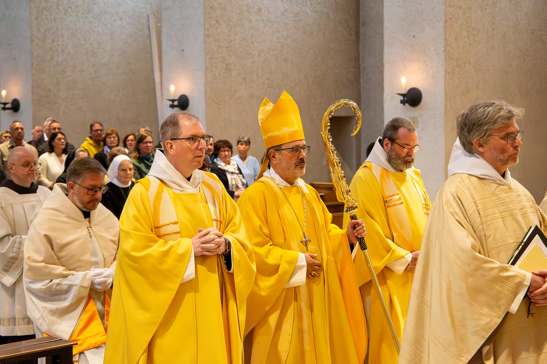 Abt und zwei Priester im gelben Gewandt beim Einzug in die Kirche