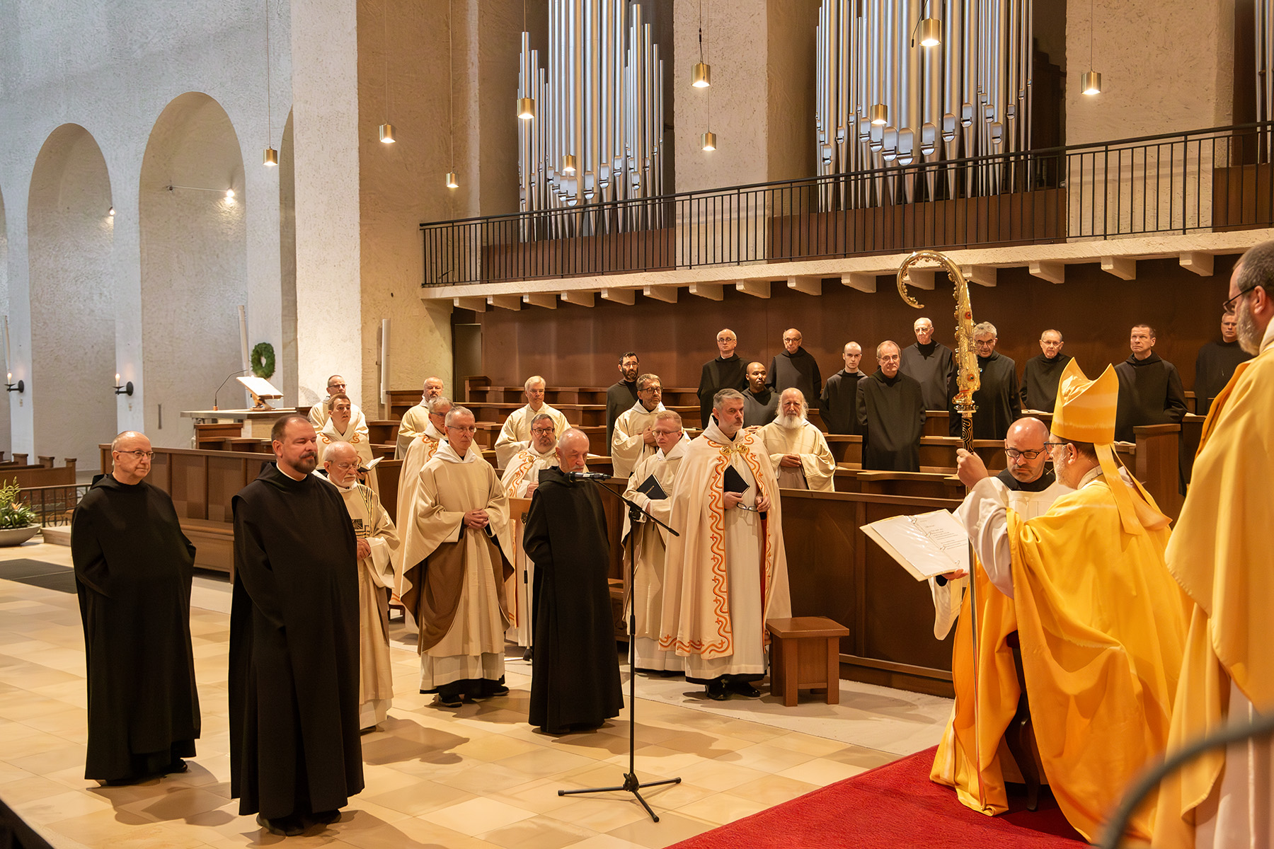 Gruppe von Mönchen steht in der Kirche vor dem Abt, der auf einem Stuhl sitzt