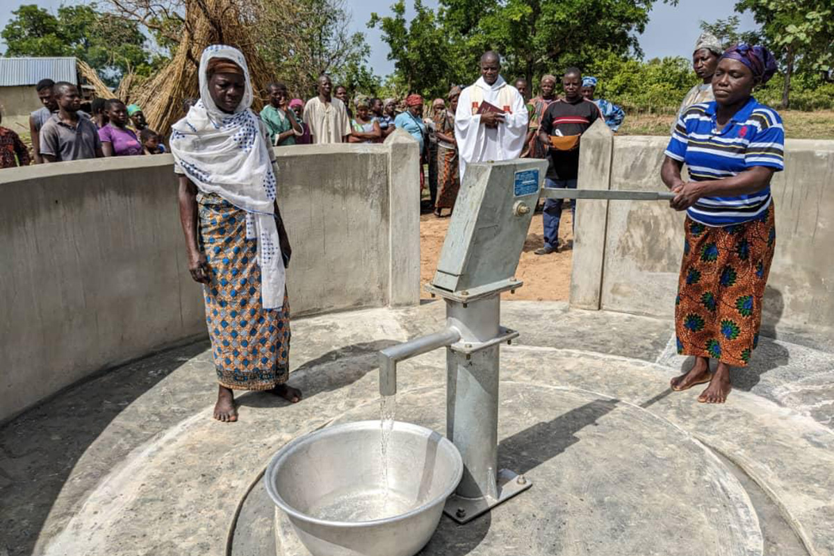 Zwei afrikanische Frauen pumpen Wasser in eine silberne Metallschüssel