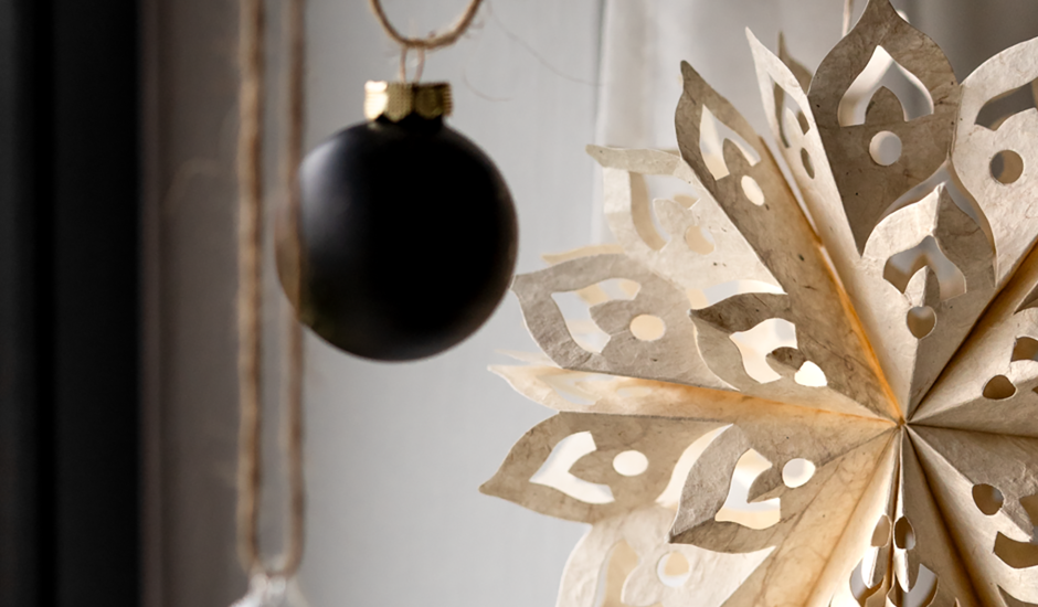 Schwarze Christbaumkugel und Papierstern